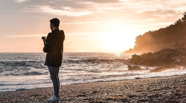 海岸で夕陽を撮影するフォトグラファー